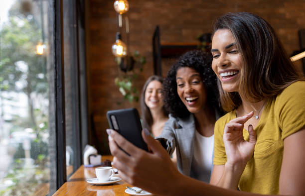 grupo de amigos en un café mirando las redes sociales en un teléfono celular - coffee buzz fotografías e imágenes de stock