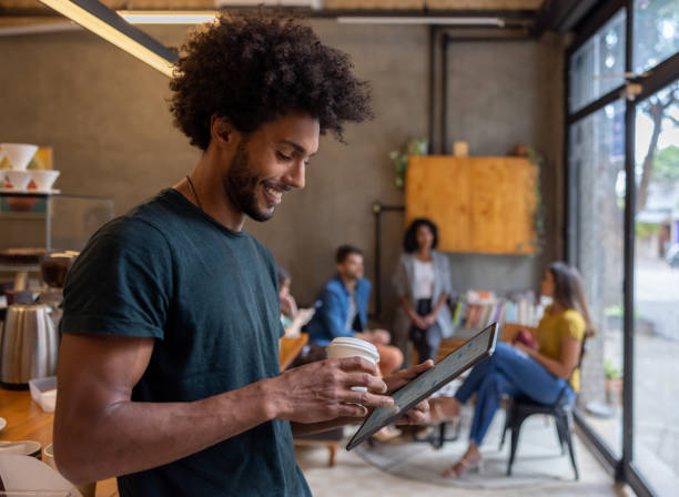 istock Happy man working online at a cafe while drinking a cup of coffee 1388431064