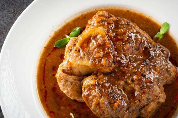 istock Stewed Osso Buco dish with tomato gravy on a white plate and a stone background, close up 1388431676