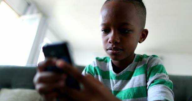 istock African child holding smartphone device. Mixed race kid using cellphone 1388431736