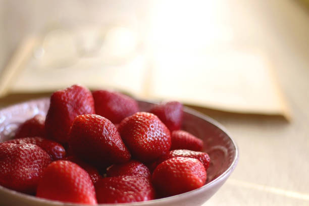 istock Bowl of Strawberries, Open Book and Reading Glasses 1388432444
