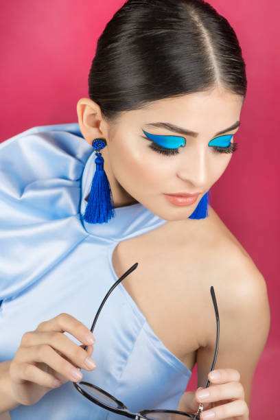 Beautiful african woman wearing fashion makeup in a studio against a grey background. Portrait of a woman with closed eyes wearing sportswear and bright blue eyeshadow. Beauty and glamour