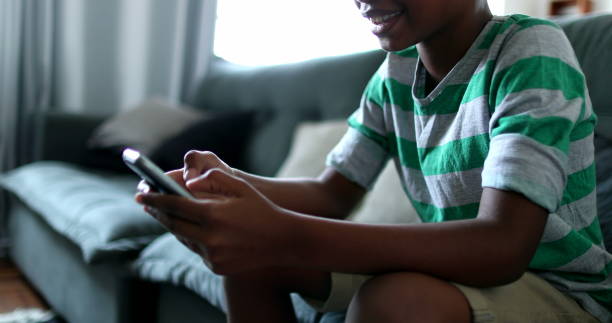 istock Child holding smartphone device. Mixed race black african boy kid using cellphone at home 1388432662