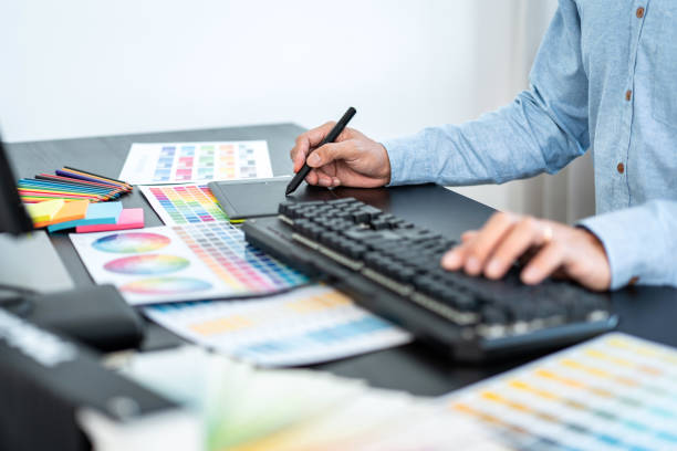 istock Young creative graphic designer working on color selection and drawing on graphics tablet at workplace, Color swatch samples chart for selection coloring 1388432726