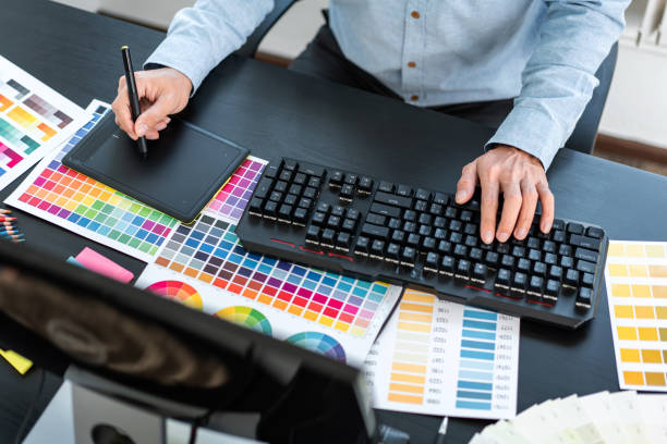 istock Young creative graphic designer working on color selection and drawing on graphics tablet at workplace, Color swatch samples chart for selection coloring 1388432732