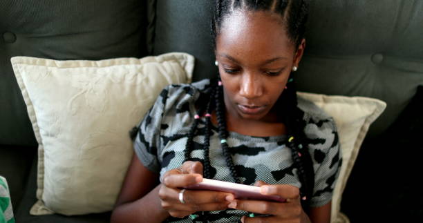 istock African siblings using cellphone at home. Black ethnicity children watching video on cellphone 1388432929