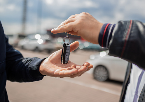 lose up. Hand giving a car key. Concept of successful car transaction sale-purchase deal