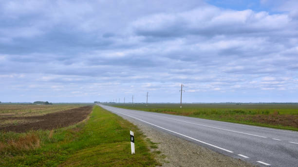 istock View of the asphalt road going beyond the horizon, passing by the fields. 1388434545