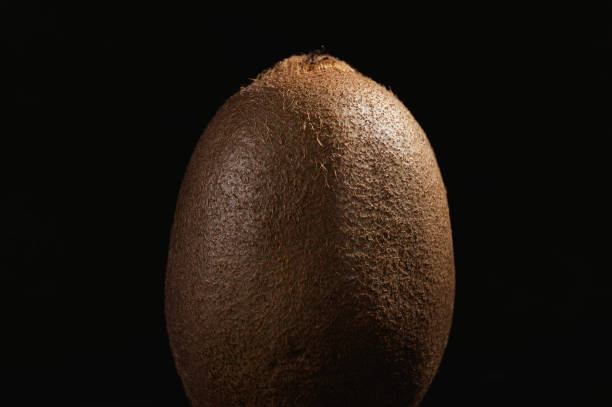 A single kiwi fruit on a black background.