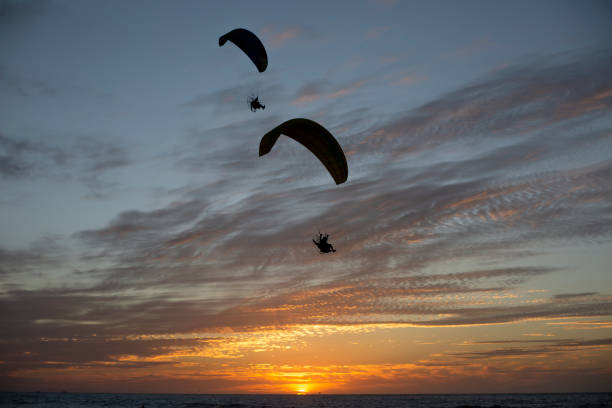 istock Silhouetted in the sky with paragliding. 1388435504