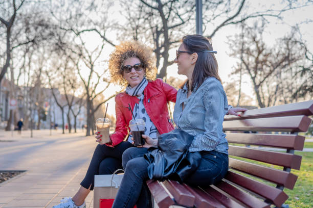 istock Friends talking and drinking coffee in a park 1388436610