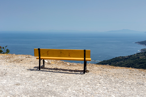 Panoramic view of the sea, mountains in the distance and a bench on a sunny summer day (Greece, Pelion)