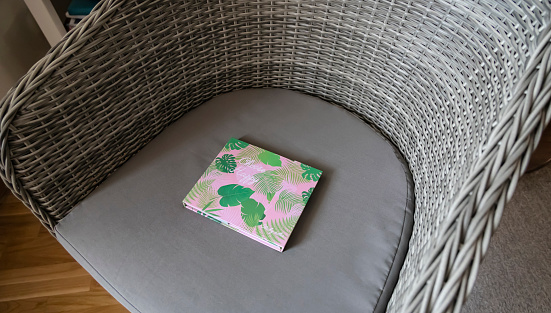 Pink notebook with green leaves print on the grey chair