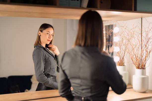 istock Lovely woman looking at her reflection in the mirror 1388444634