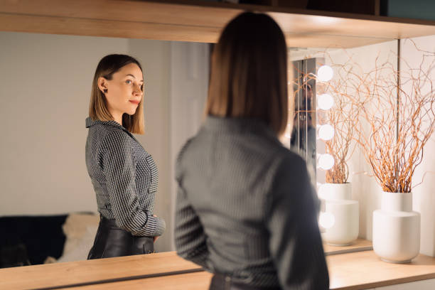 istock Lovely woman looking at her reflection in the mirror 1388444636