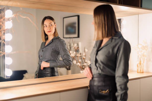 istock Lovely woman looking at her reflection in the mirror 1388444640