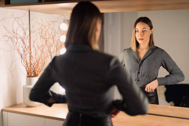 istock Lovely woman looking at her reflection in the mirror 1388444642