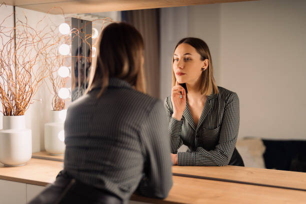 istock Lovely woman looking at her reflection in the mirror 1388444650