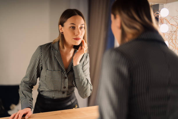 istock Lovely woman looking at her reflection in the mirror 1388444652