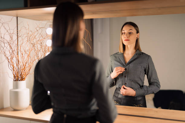 istock Lovely woman looking at her reflection in the mirror 1388444695