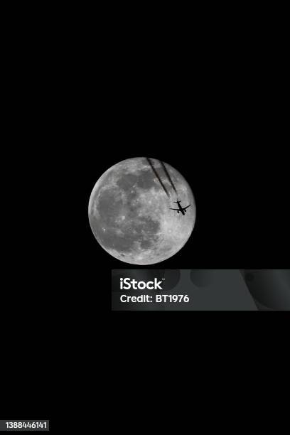 A Jet Flying Under A Full Moon At Night Color Image Stock Photo - Download Image Now