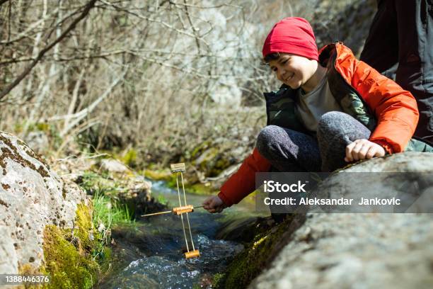 A Curious Boy Testing A Water Wheel In A Mountain Stream Stock Photo - Download Image Now