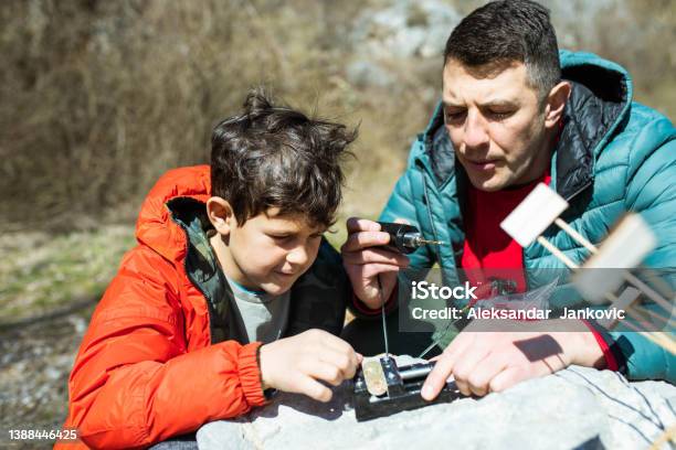 Crafty Father And Son Making A Waterwheel Outdoors Stock Photo - Download Image Now - Building - Activity, Environmental Conservation, Making