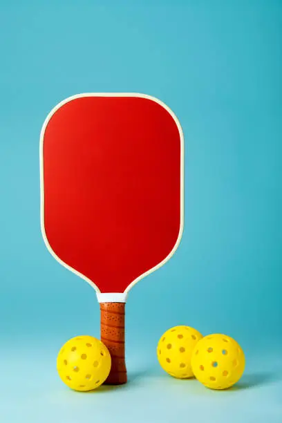 Photo of Red Pickleball Paddle and Yellow Balls on Blue Background