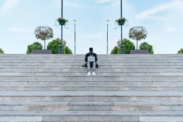 istock African American man in suit working on laptop computer sitting on stairs alone 1388449101