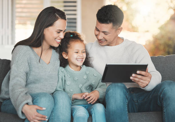 istock Shot of a young family happily bonding while using a digital tablet together on the sofa at home 1388450387