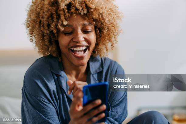 Smiling Woman Using Mobile Phone In The Bedroom Stock Photo - Download Image Now - Women, One Woman Only, Mobile Phone