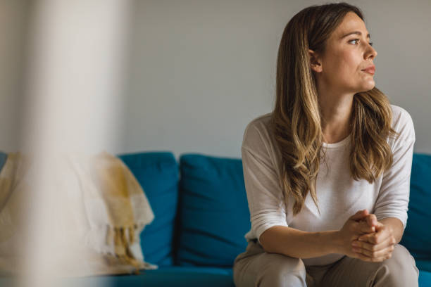 istock Anxious young woman sitting on the sofa, cracking her knuckles and contemplating 1388452940