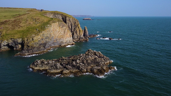 wild cliffs of the cooper coast, waterford ireland. in drone flight with azure water and calm atlantic sea
