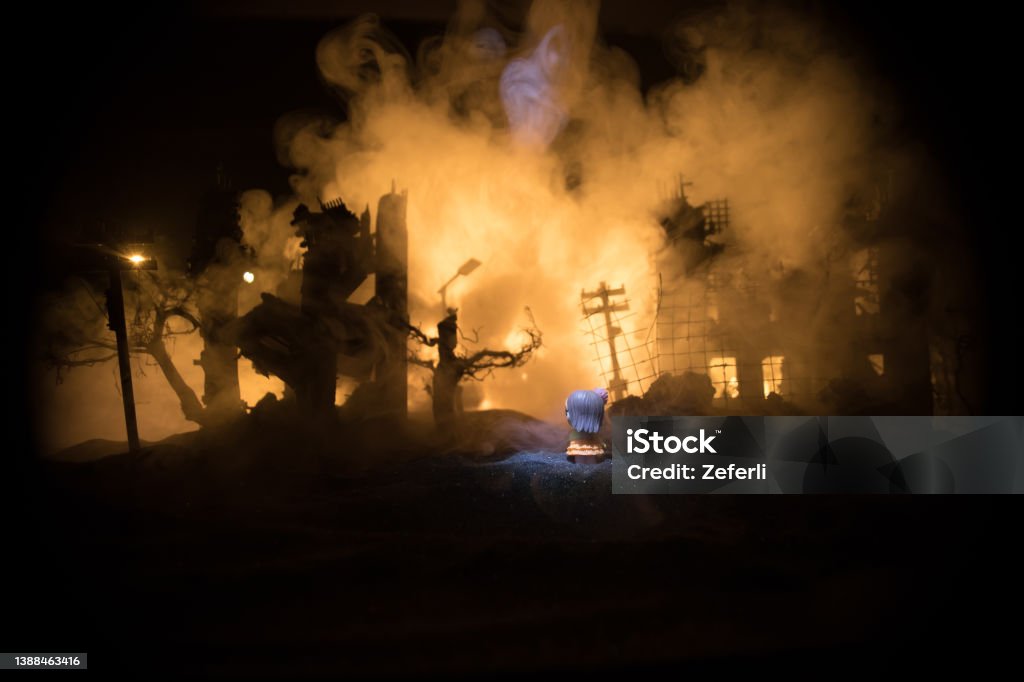 Creative artwork of little doll lies on ground in burned out city. Selective focus Mariupol Stock Photo