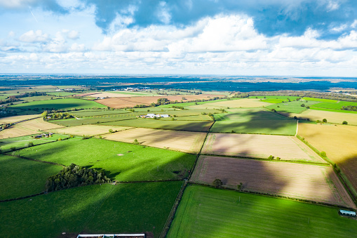 Aerial view of beautiful agricultural fields with cloudy blue sky in England