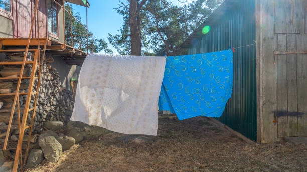 istock Bedding sheets drying on the clothesline outside. Lens flare. Bed linen drying on a clothes line in the garden. 1388465347