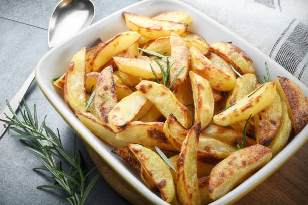 istock Crispy roast potatoes with rosemary in baking dish on gray background. 1388465957
