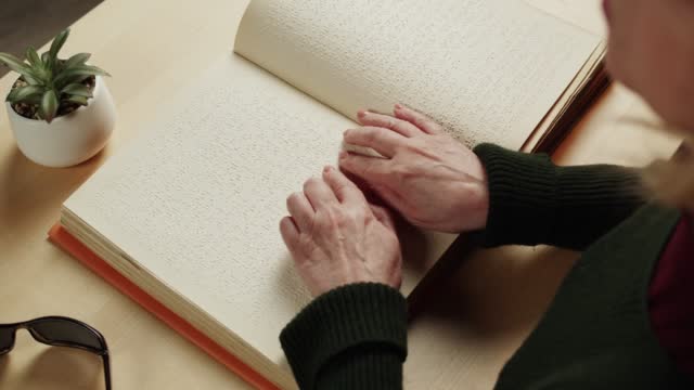 Blind woman reading braille book top view, poorly seeing female person learning to read, home education for people with disabilities, touching letters on sheet of paper.