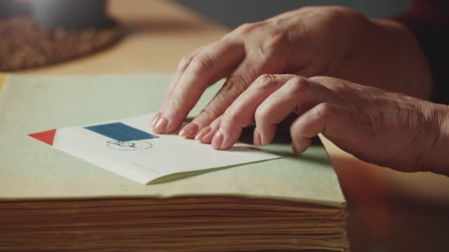 Blind woman reading postcard, braille, using fingers close-up, poorly seeing female person learning to read, home education for people with disabilities, touching letters on sheet of paper.