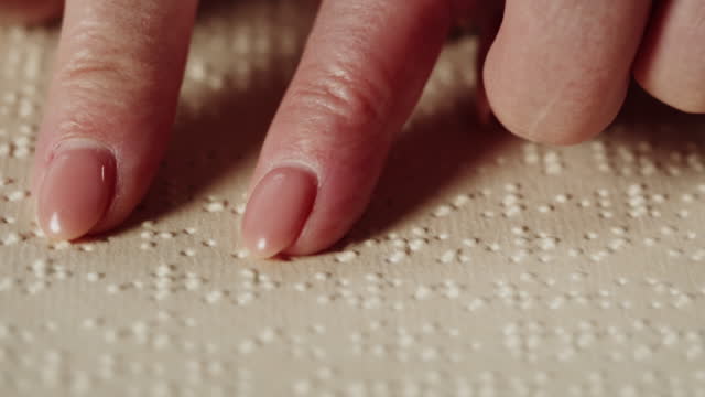 Blind woman reading braille book using fingers close-up, poorly seeing female person learning to read, home education for people with disabilities, touching letters on sheet of paper.