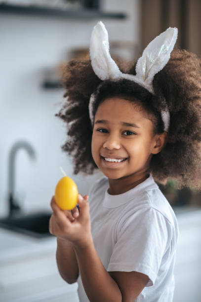 istock Cute girl wuth bunny ears holding an egg in hands and smiling 1388478179