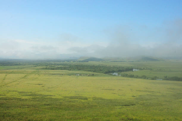 istock A flat huge steppe with a flowing river and mountains covered by clouds. 1388489729