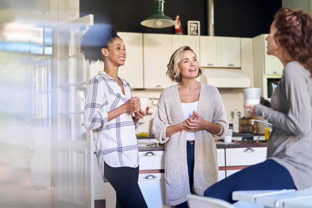 istock Female friends having coffee in kitchen while having a good time 1388493022