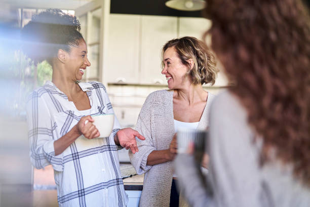 istock Female friends laughing out loud while standing in kitchen 1388493039
