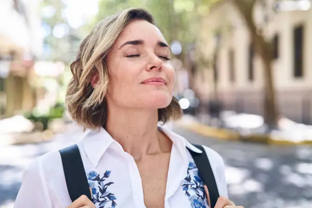 Photo of Adult woman taking deep breath while standing on street