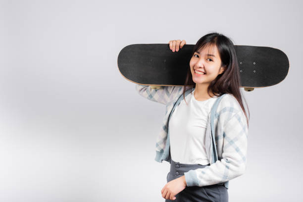 istock Smiling happy woman holding skateboard on shoulder 1388495052