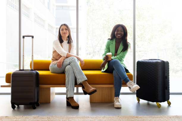 istock Multiracial young women sitting on hotel reception bench looking at camera 1388495657