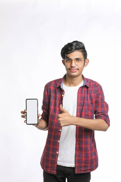 istock Young indian college student showing smartphone Screen on white background. 1388499728