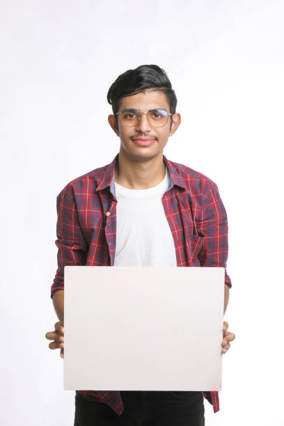 istock Young Indian man showing blank sing board over white background 1388499737