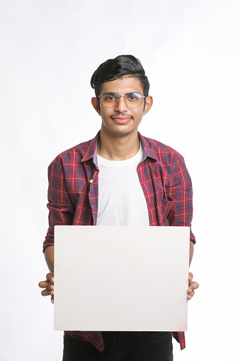 Young Indian man showing blank sing board over white background